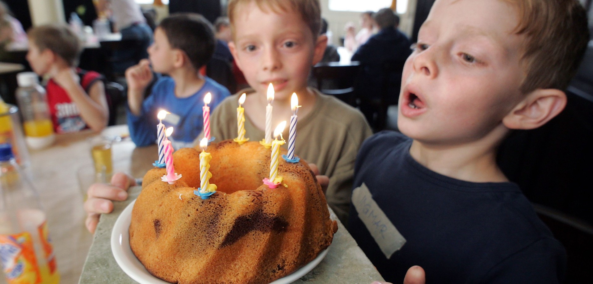 Ein Kind pustet Kerzen auf dem Geburtstagskuchen aus.