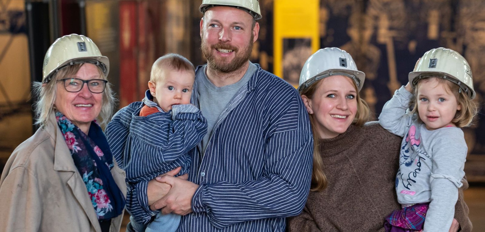 Eine Familie mit zwei Kindern bekleidet mit Bergmannshemden und Helmen.