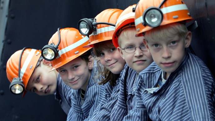 Vier Kinder mit Bergarbeiterhelmen- und Hemden Vier Kinder mit Bergarbeiterhelmen- und Hemden