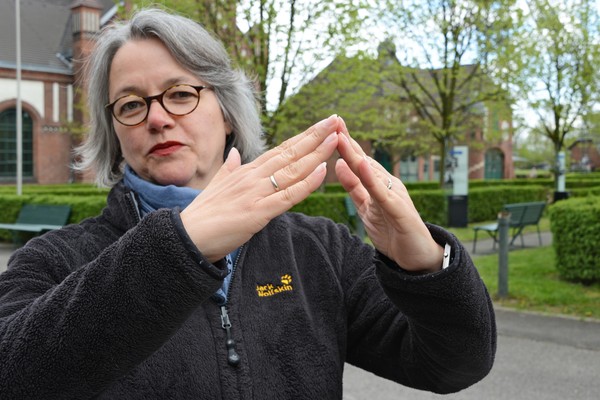 Gebärdendolmetscherin macht mit den Händen die Gebärde für ein Gebäude