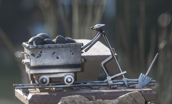 Kleine Skulptur aus Stahl: ein Mann schiebt einen Förderwagen mit Kohle.