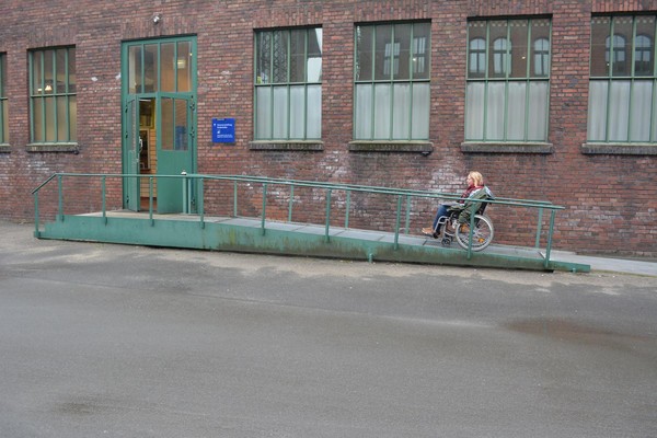 Rollstuhlfahrerin auf der Rampe zum Eingang der Ausstellung.