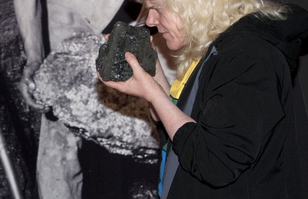 Eine Besucherin riecht an einem Stück Kohle, das sie in den Händen hält.