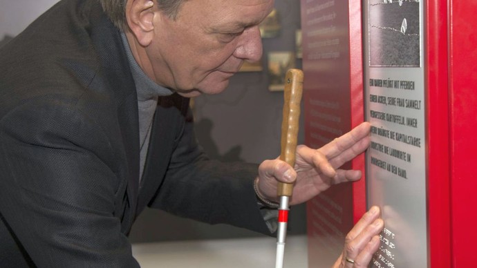 Ein Mann berührt Braille-Schrift auf einer Ausstellungstafel. Ein Mann berührt Braille-Schrift auf einer Ausstellungstafel.