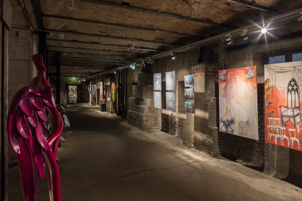 Blick in den Keller der Maschinenhalle mit Bildern und einer Skulptur der Ausstellung PostMost